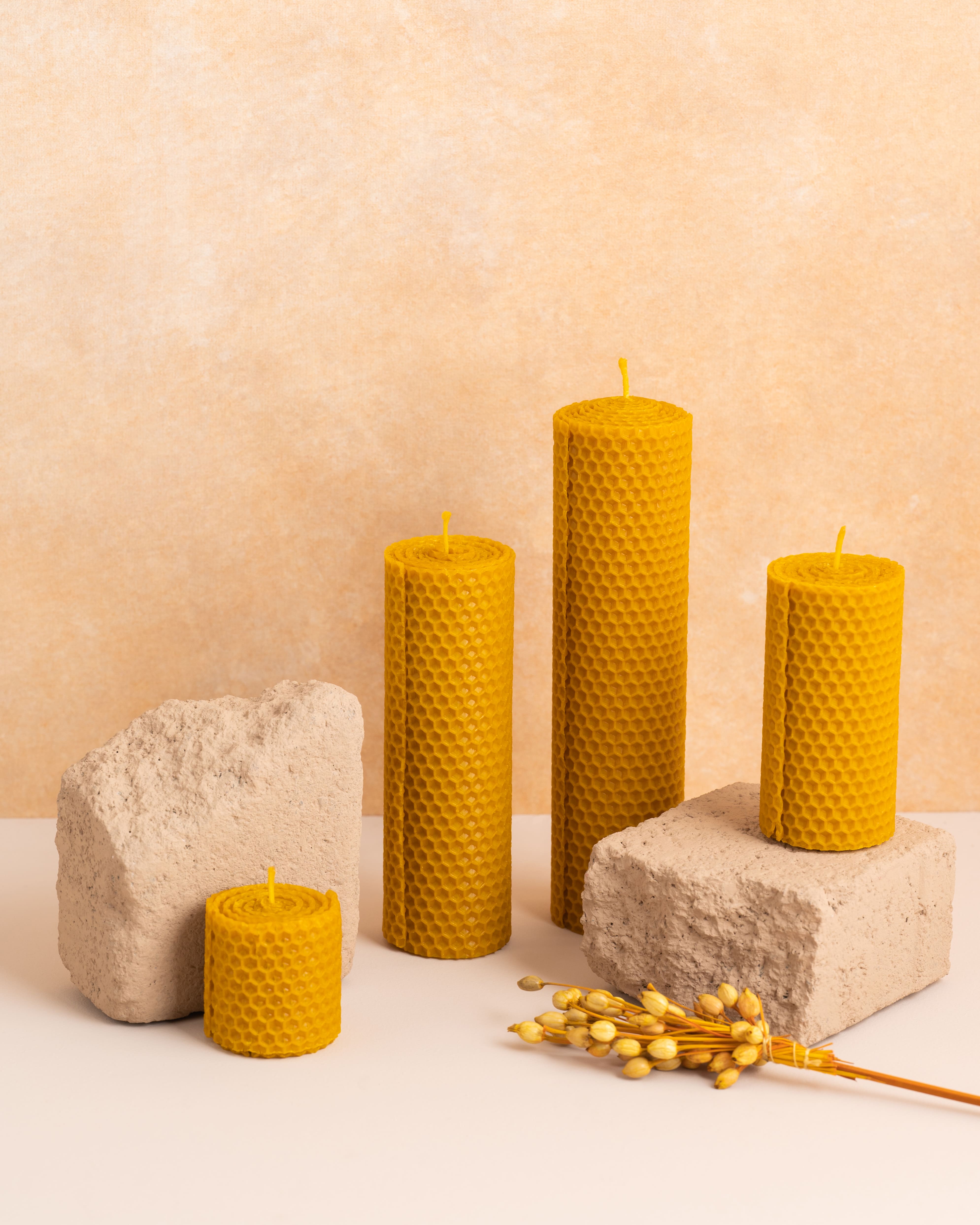 Conjunto de velas artesanais em cera de abelha pura com 5cm, 10cm, 15cm e 20cm de altura. Cada peça é feita a partir de folhas de cera enroladas, exibindo o padrão hexagonal natural dos favos de mel. Um conjunto sustentável e elegante para decoração ou presente.