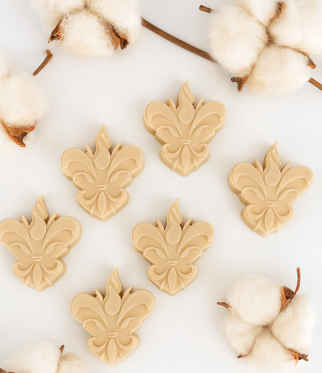 Pack de 6 wax melts Sweet Glade da Candlys, em tom bege e formato flor-de-lis, fotografados num cenário clean com ramos de algodão. Fragrância: madeira de sândalo e baunilha. Coleção Algodão Colorido.