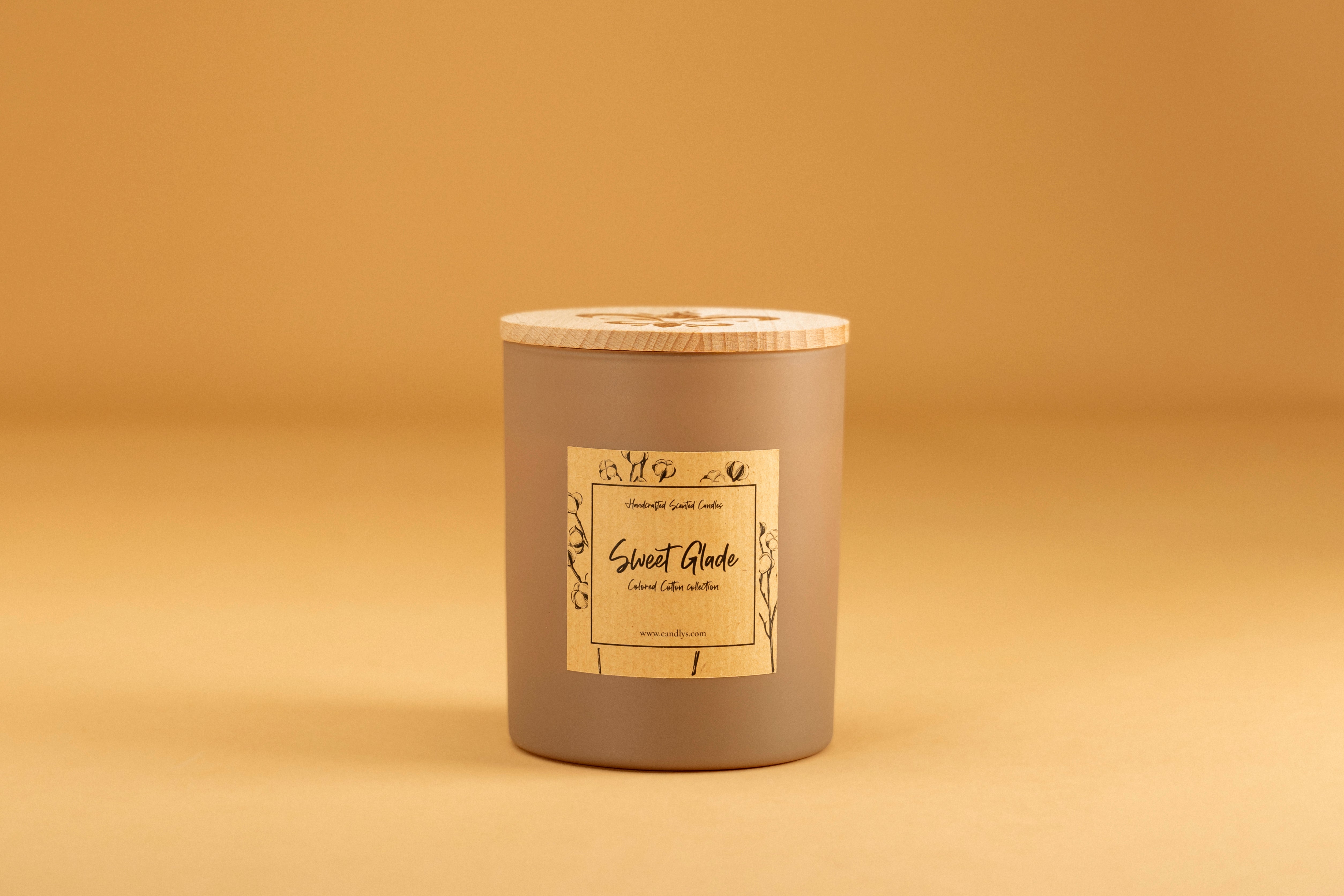 Vela Sweet Glade em fundo laranja quente, destacando o rótulo e frasco elegante – Candlys.