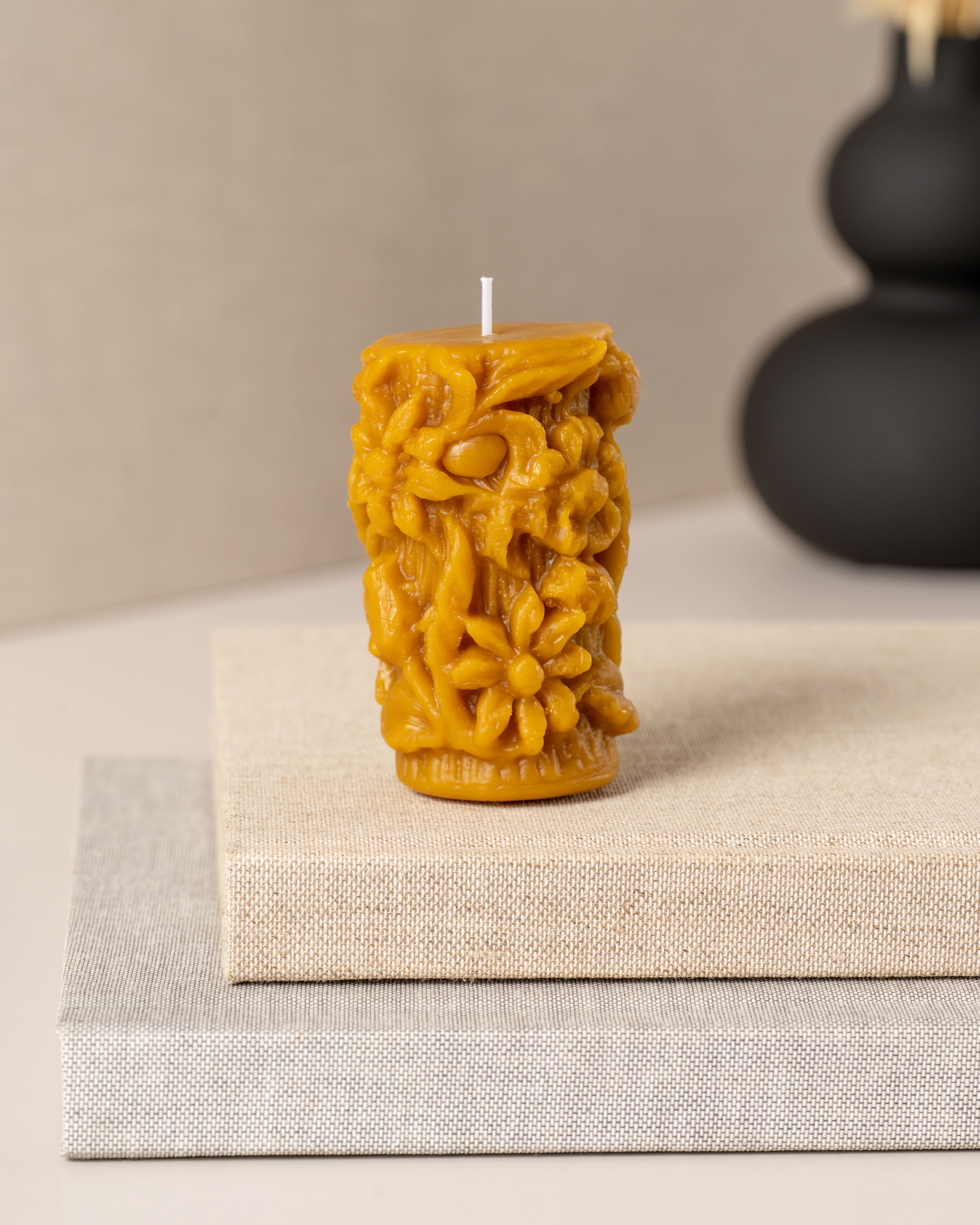 Vela artesanal em cera de abelha pura da Candlys, com design altamente detalhado em relevo de flores e plantas do campo. Um trabalho minucioso que combina beleza decorativa com o aroma naturalmente doce da cera de abelha.