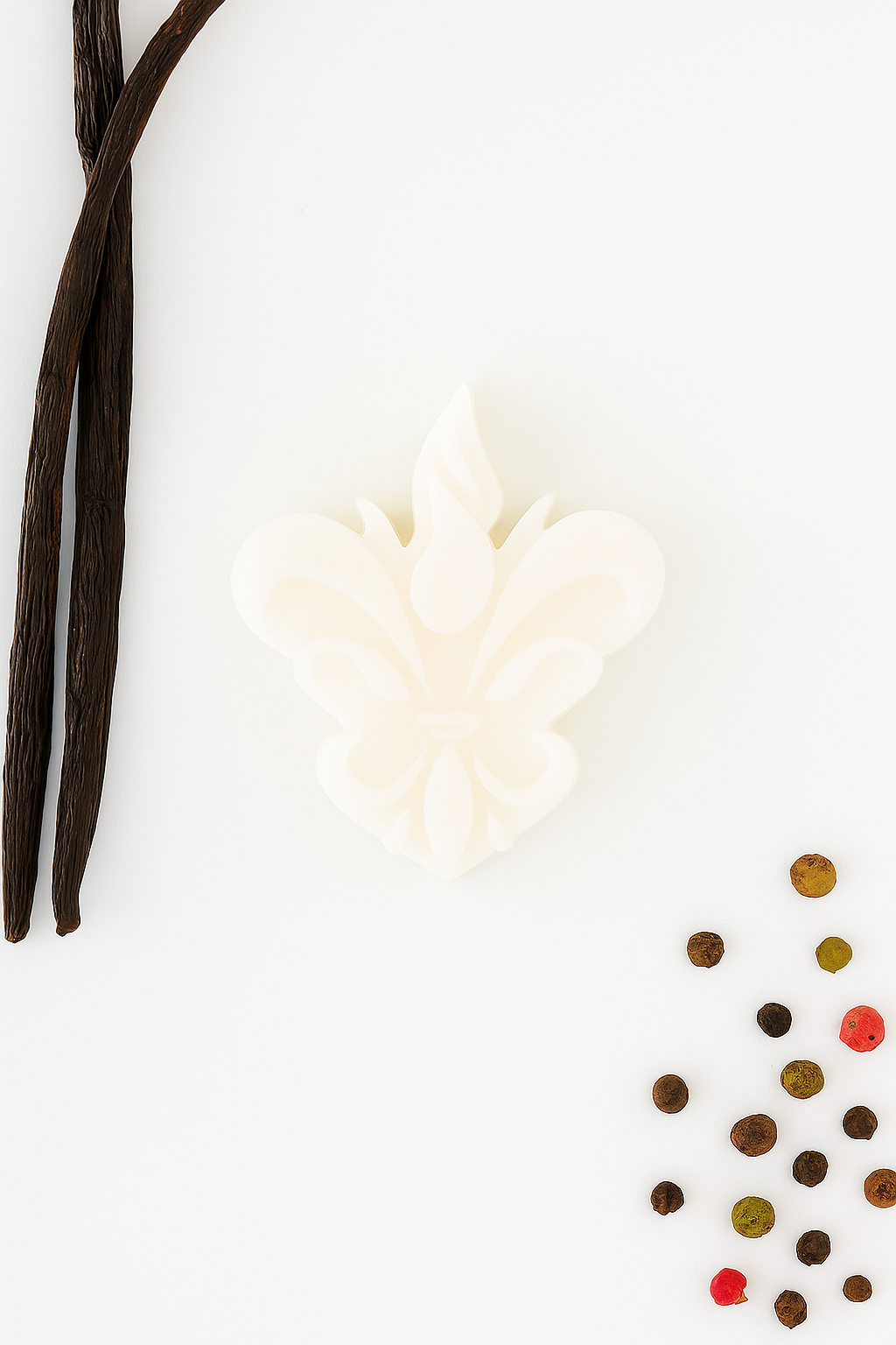 Wax melt artesanal branco em forma de flor-de-lis, acompanhado por vagens de baunilha e grãos de pimenta coloridos, representando a edição especial Jar of Love – Baunilha e Especiarias da Candlys.