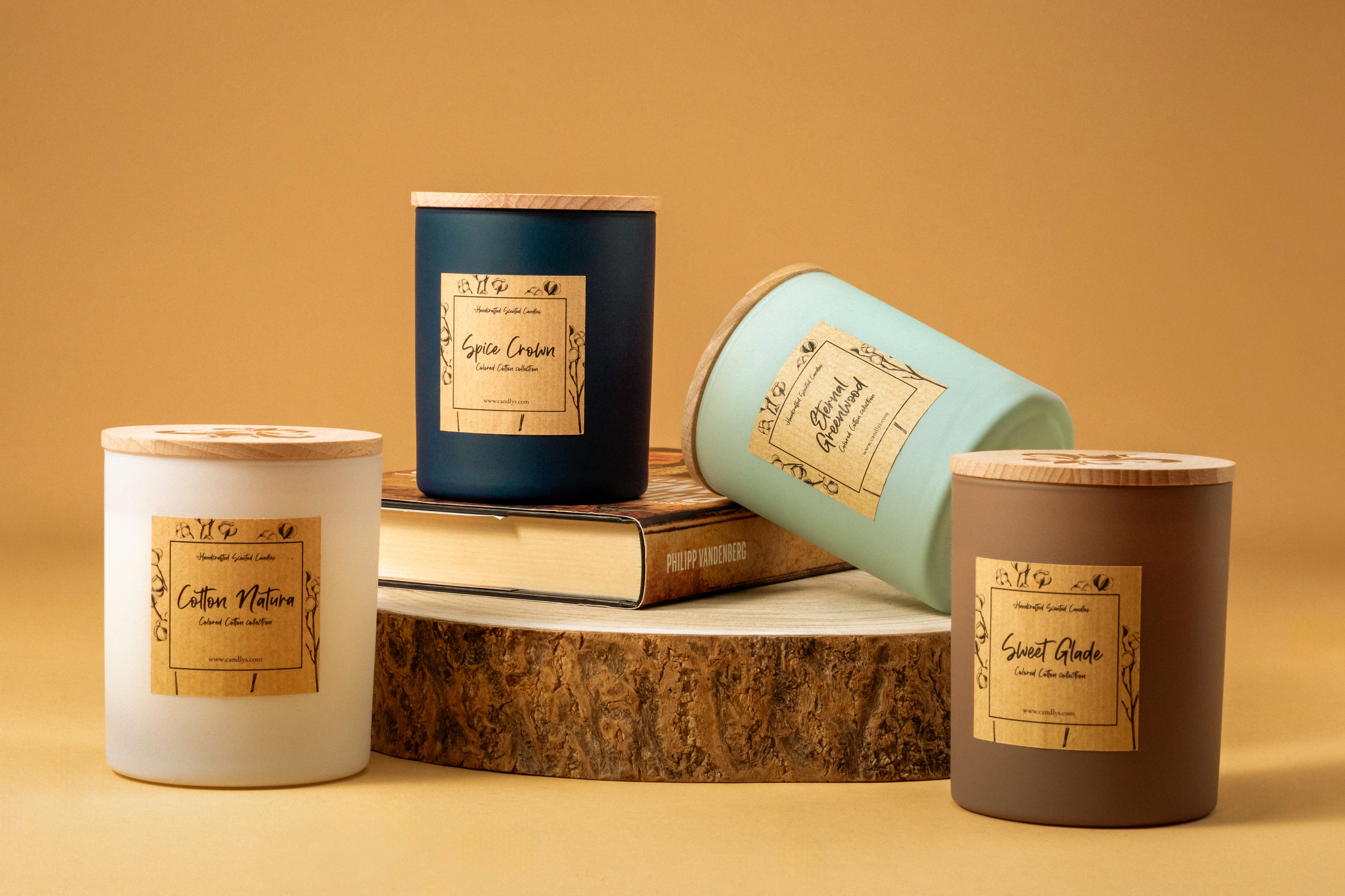 Coleção de velas Candlys em copos coloridos mate, incluindo a Sweet Glade em castanho, a Cotton Natura em branco, a Eternal Greenwood em verde, a Spice Crown em azul, em cenário decorativo.