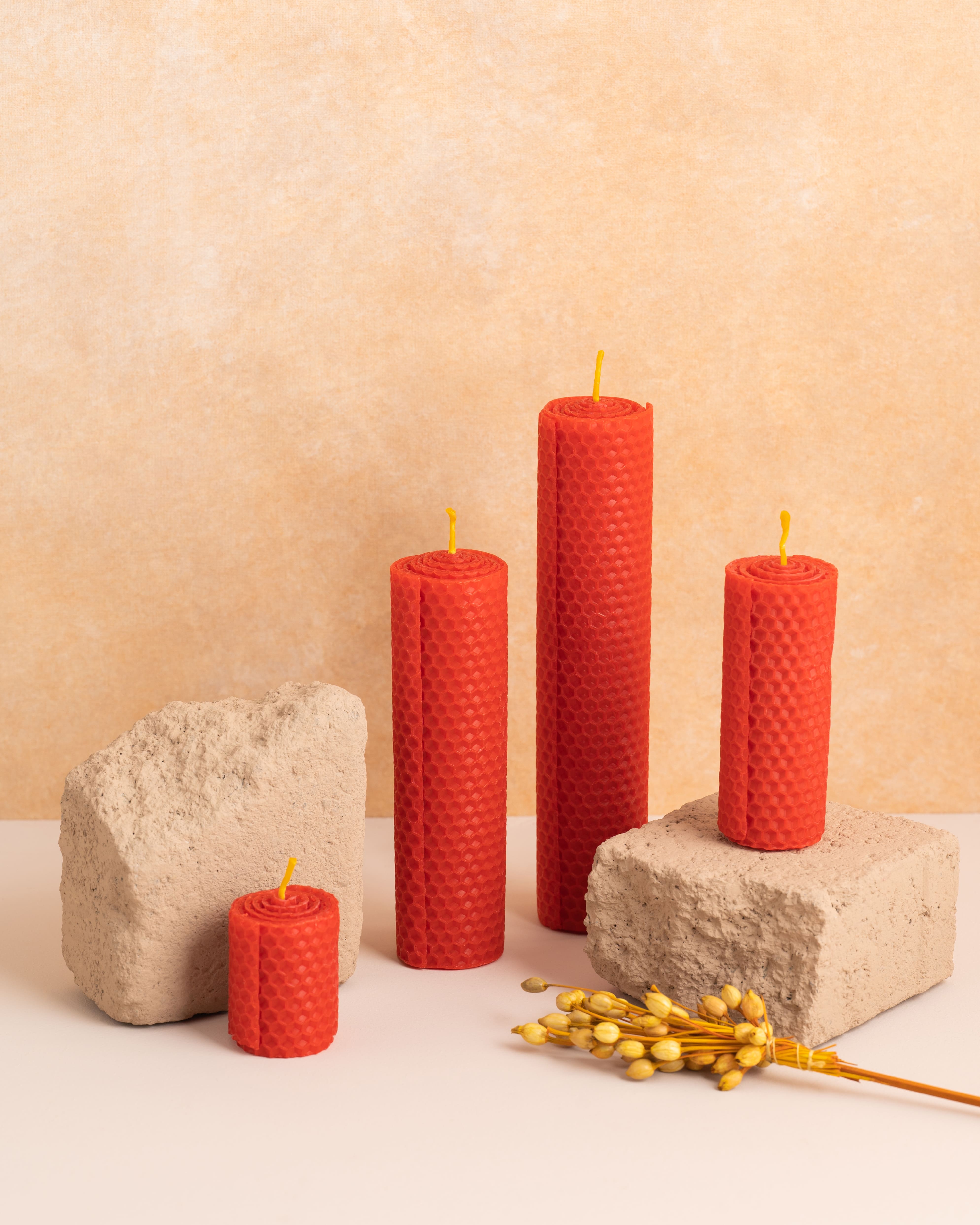 Conjunto de três velas artesanais em cera de abelha cor escarlate, com alturas de 5 cm, 10 cm, 15 cm e 20cm. Produzidas a partir de folhas de cera enroladas com padrão hexagonal de favos de mel, perfeitas para criar uma decoração harmoniosa e sustentável.