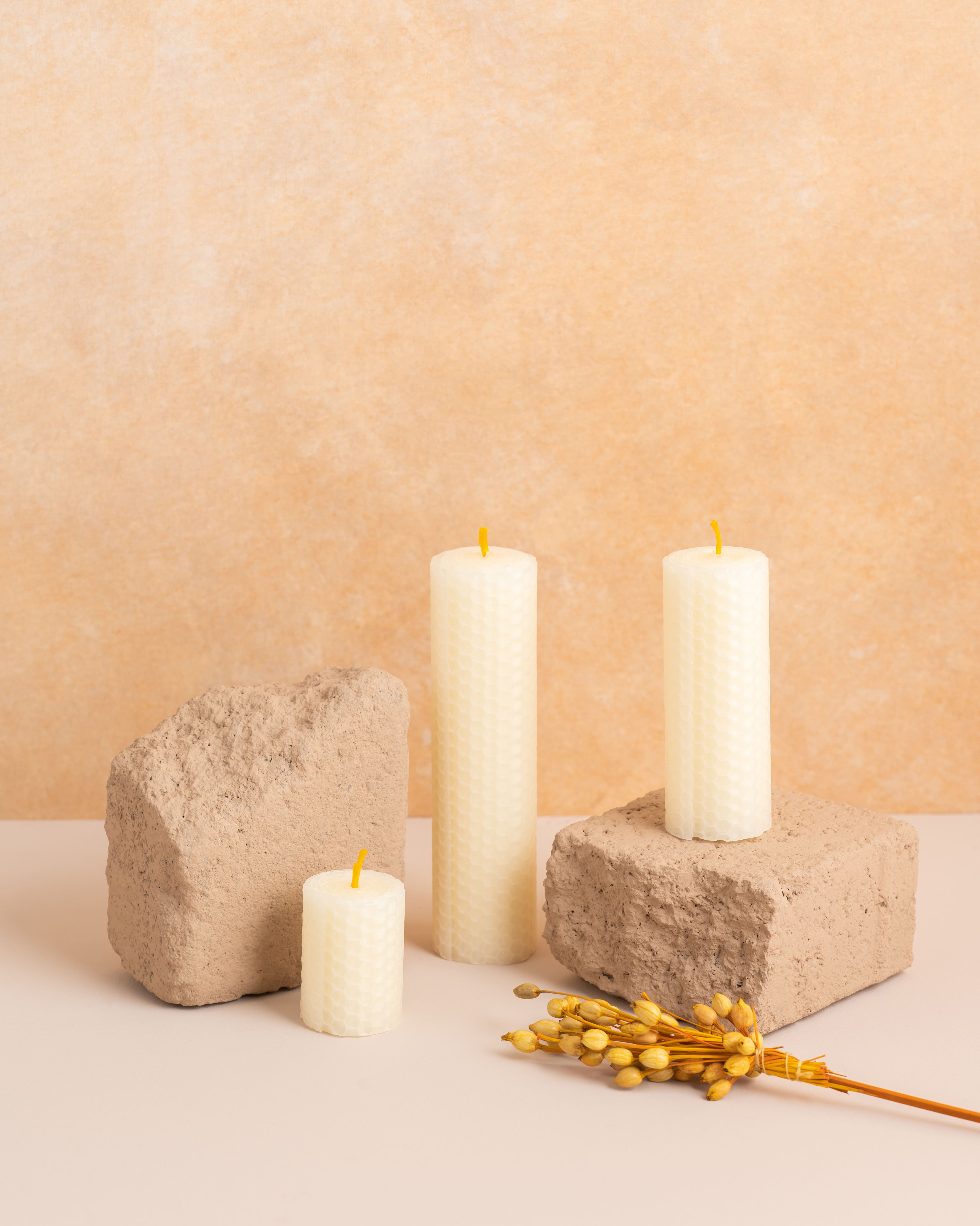 Conjunto de três velas artesanais em cera de abelha cor pérola branco, com alturas de 5 cm, 10 cm e 15 cm. Produzidas a partir de folhas de cera enroladas com padrão hexagonal de favos de mel, perfeitas para criar uma decoração harmoniosa e sustentável.