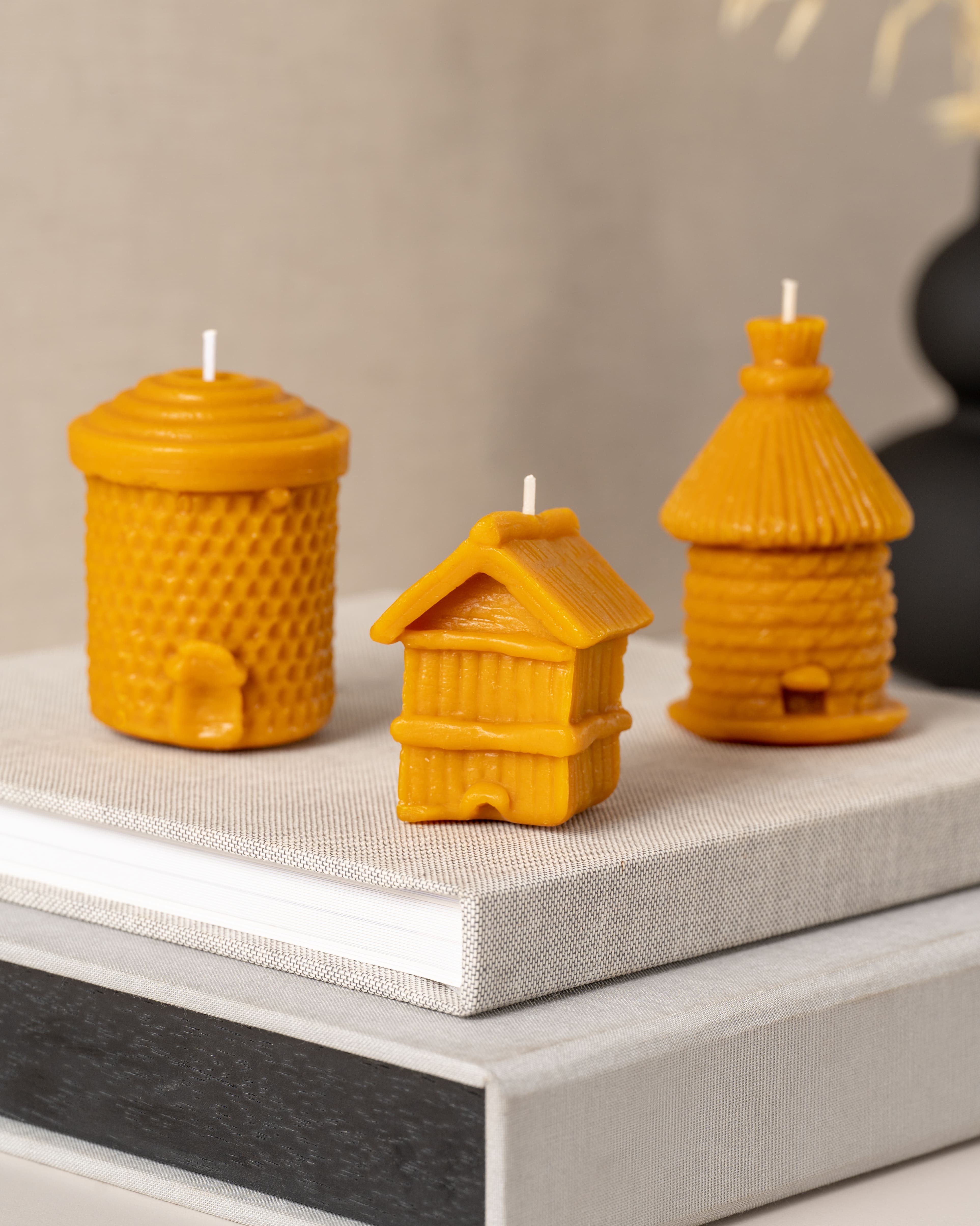 Conjunto de velas artesanais em cera de abelha pura da Candlys, incluindo modelos em forma de colmeia com favos, colmeia com telhado de palha e casa rústica, perfeitas para decoração natural e ecológica.