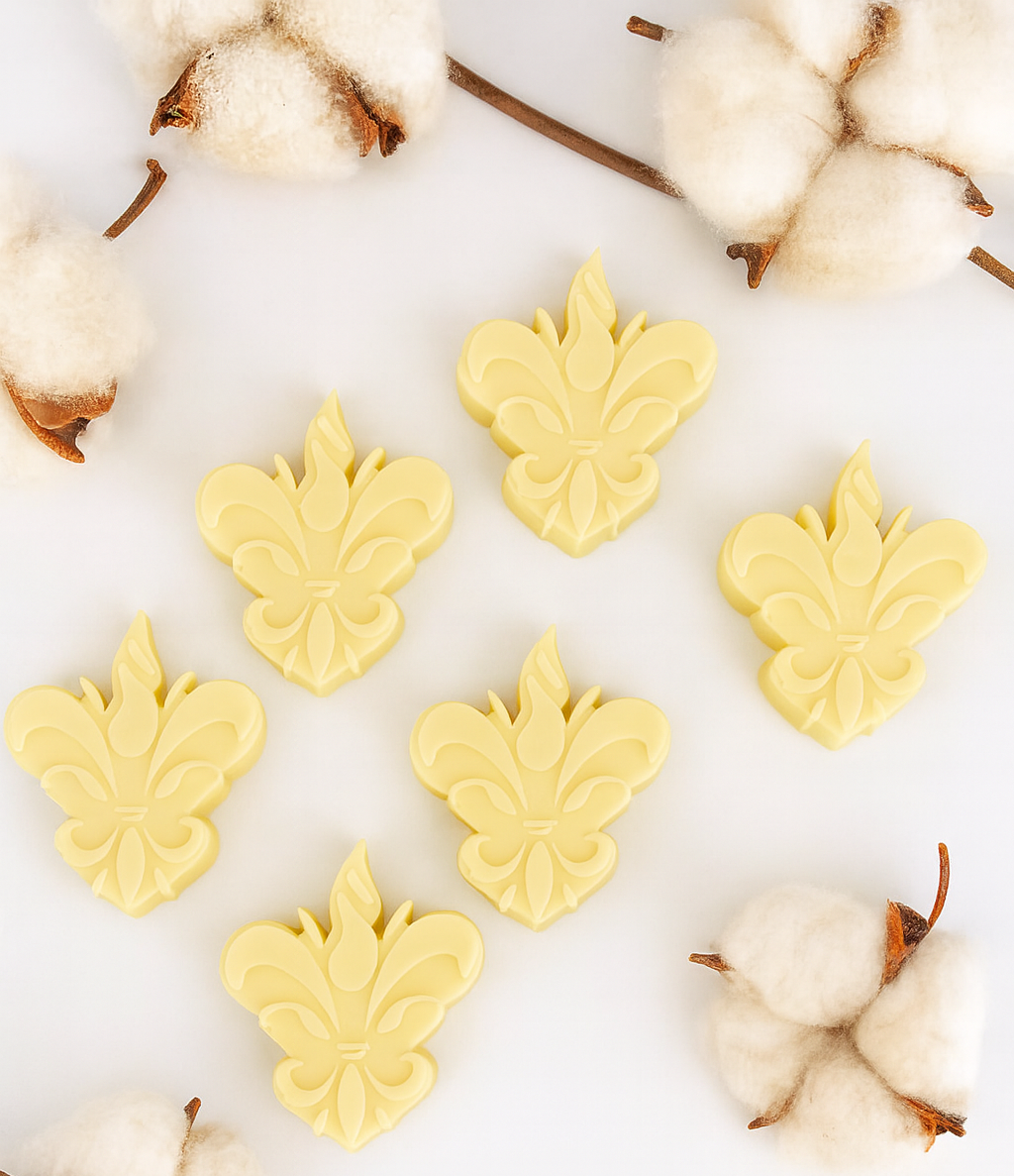 Pack de 6 wax melts Tropical Cocktail da Candlys, em amarelo pastel e formato flor-de-lis, dispostos num cenário clean com ramos de algodão. Fragrância: coco, lima e limão. Coleção Algodão Colorido.