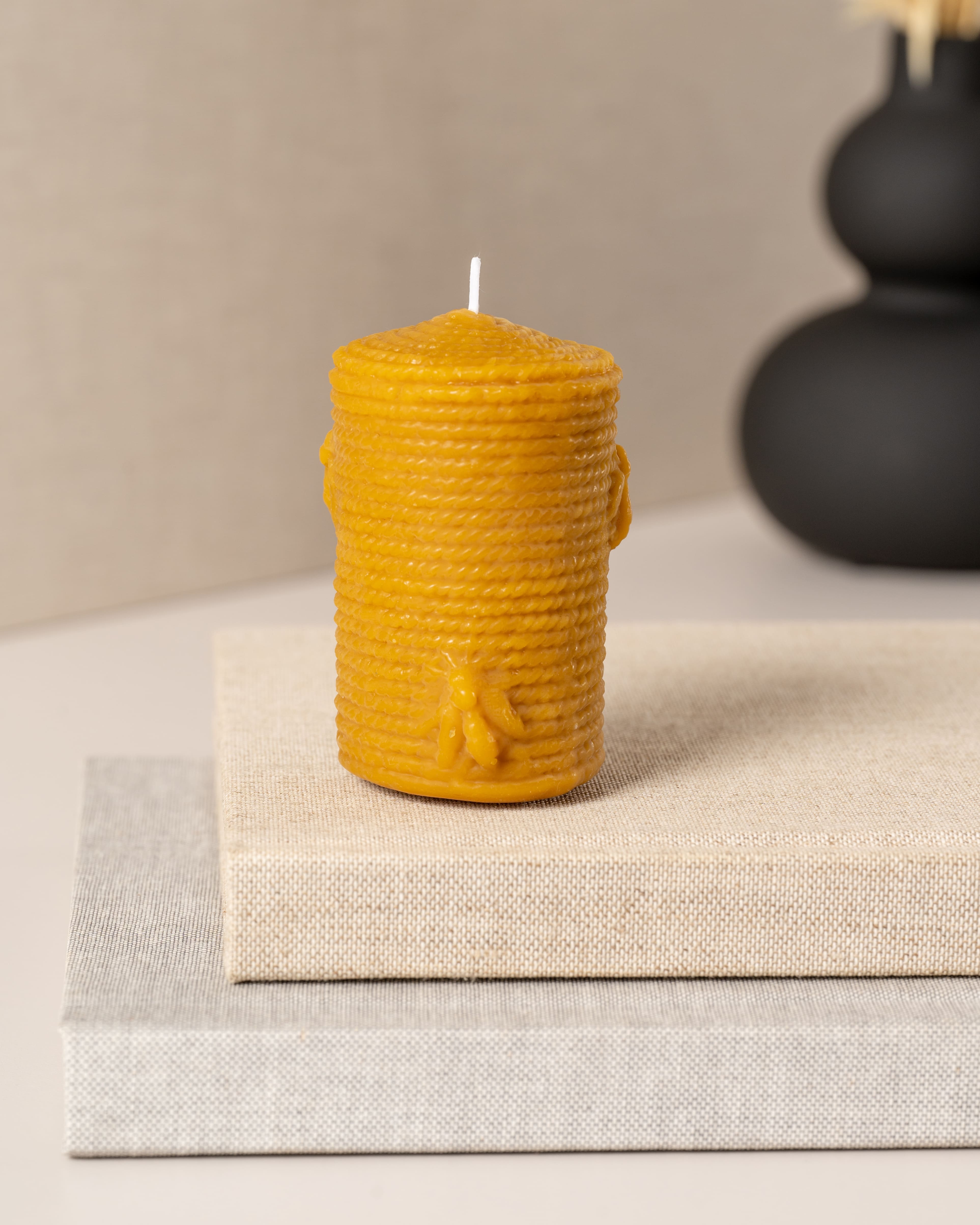 Vela artesanal cilíndrica em cera de abelha pura da Candlys, com textura em relevo que imita uma colmeia e detalhe decorativo de uma pequena abelha. Peça natural, sustentável e aromática, ideal para decoração rústica e ecológica.