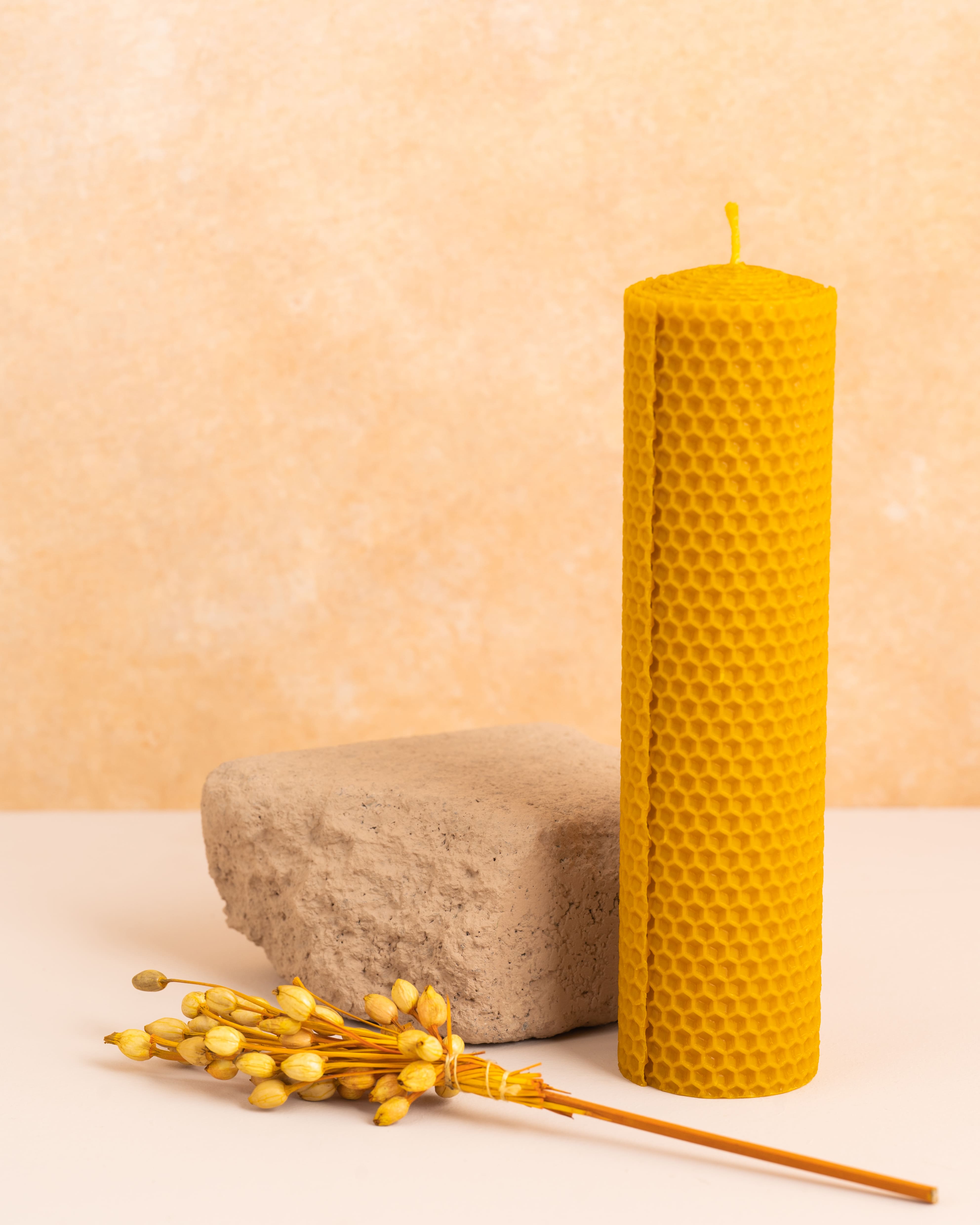 Vela artesanal de 20cm em cera de abelha pura, criada a partir de folhas de cera enroladas à mão com padrão hexagonal de favo de mel. Uma peça natural, sustentável e elegante para decoração.