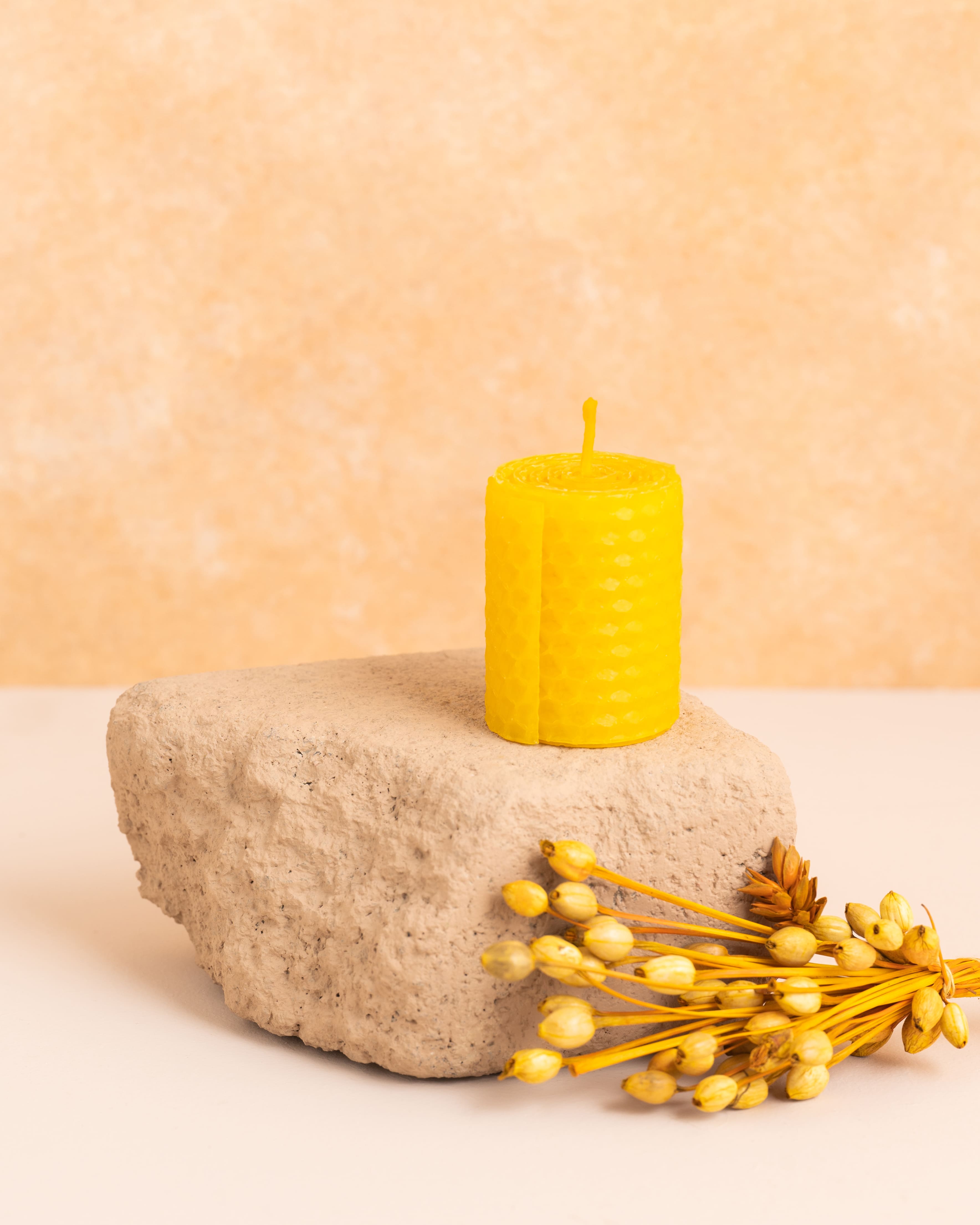 Vela artesanal em cera de abelha cor amarela com 5 cm de altura, feita a partir de folhas de cera enroladas. Textura hexagonal dos favos de mel em detalhe, elegante e minimalista para decorações delicadas.
