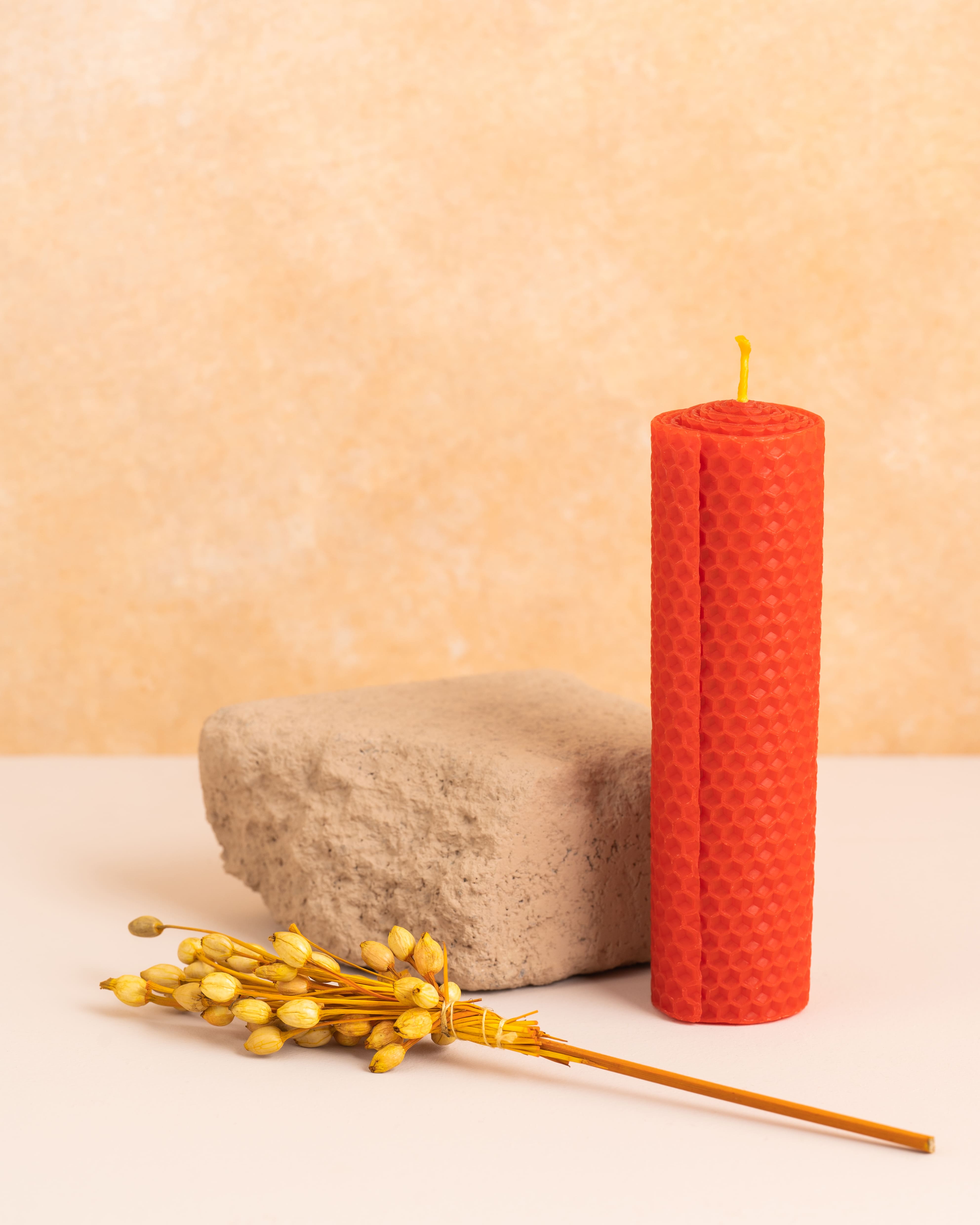 Vela artesanal em cera de abelha cor escarlate com 15 cm de altura, criada através de folhas de cera enroladas. Textura natural dos favos de mel, ideal para uma decoração clean e sustentável.