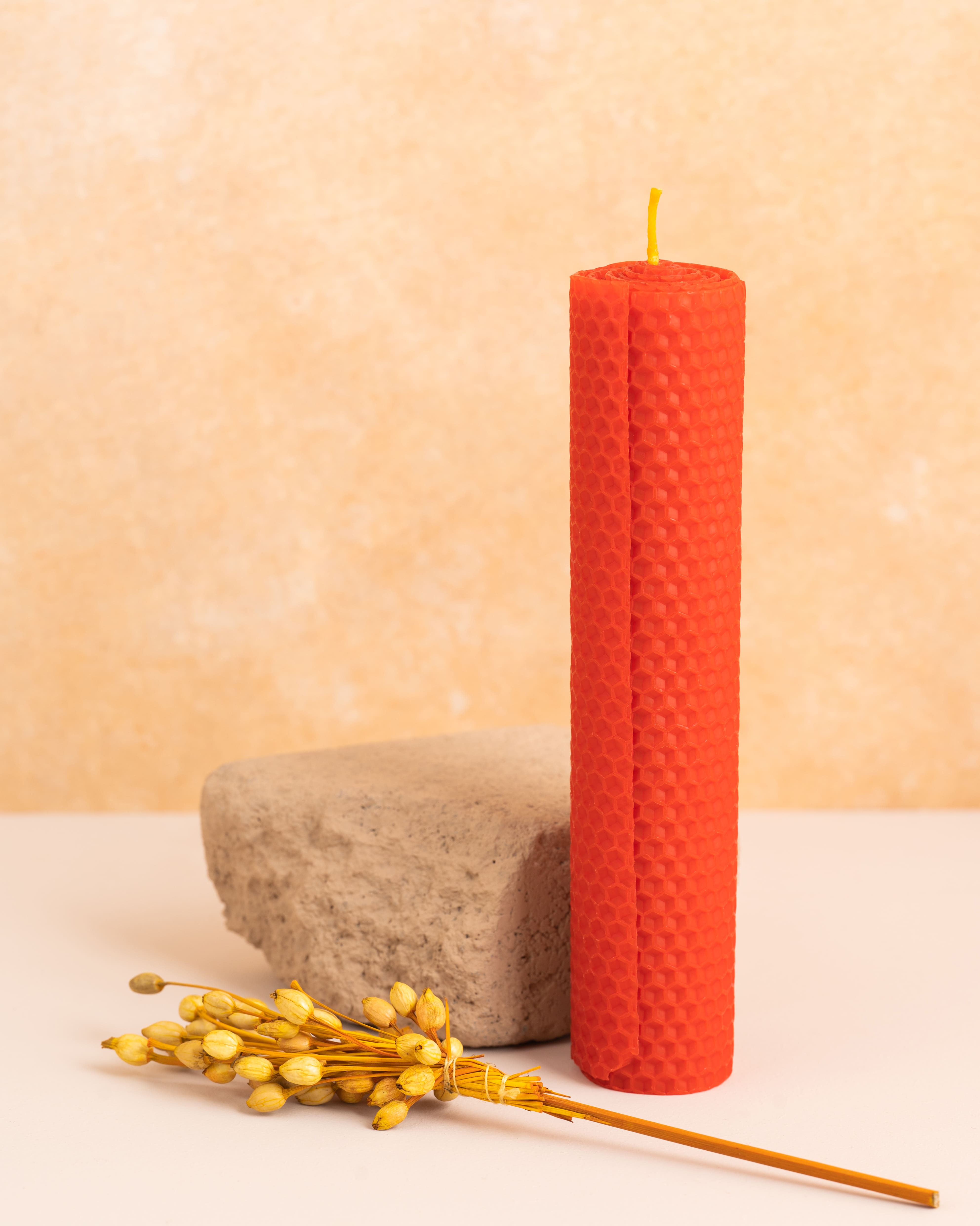 Vela alta em cera de abelha cor escarlate com 20 cm de altura, feita a partir de folhas de cera enroladas. Padrão hexagonal dos favos de mel, destacando-se como peça decorativa elegante e ecológica.