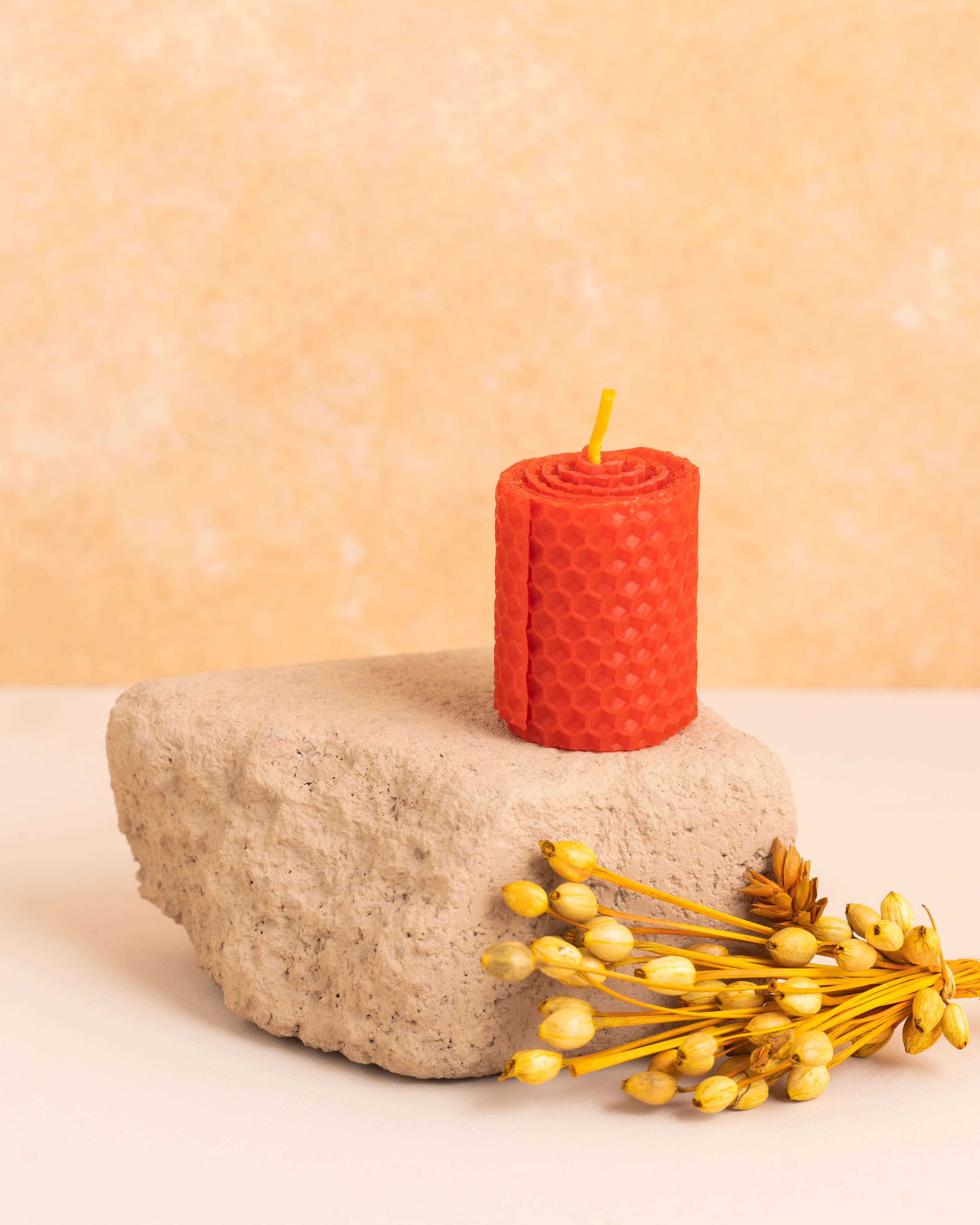 Vela artesanal em cera de abelha cor escarlate com 5 cm de altura, feita a partir de folhas de cera enroladas. Textura hexagonal dos favos de mel em detalhe, elegante e minimalista para decorações delicadas.