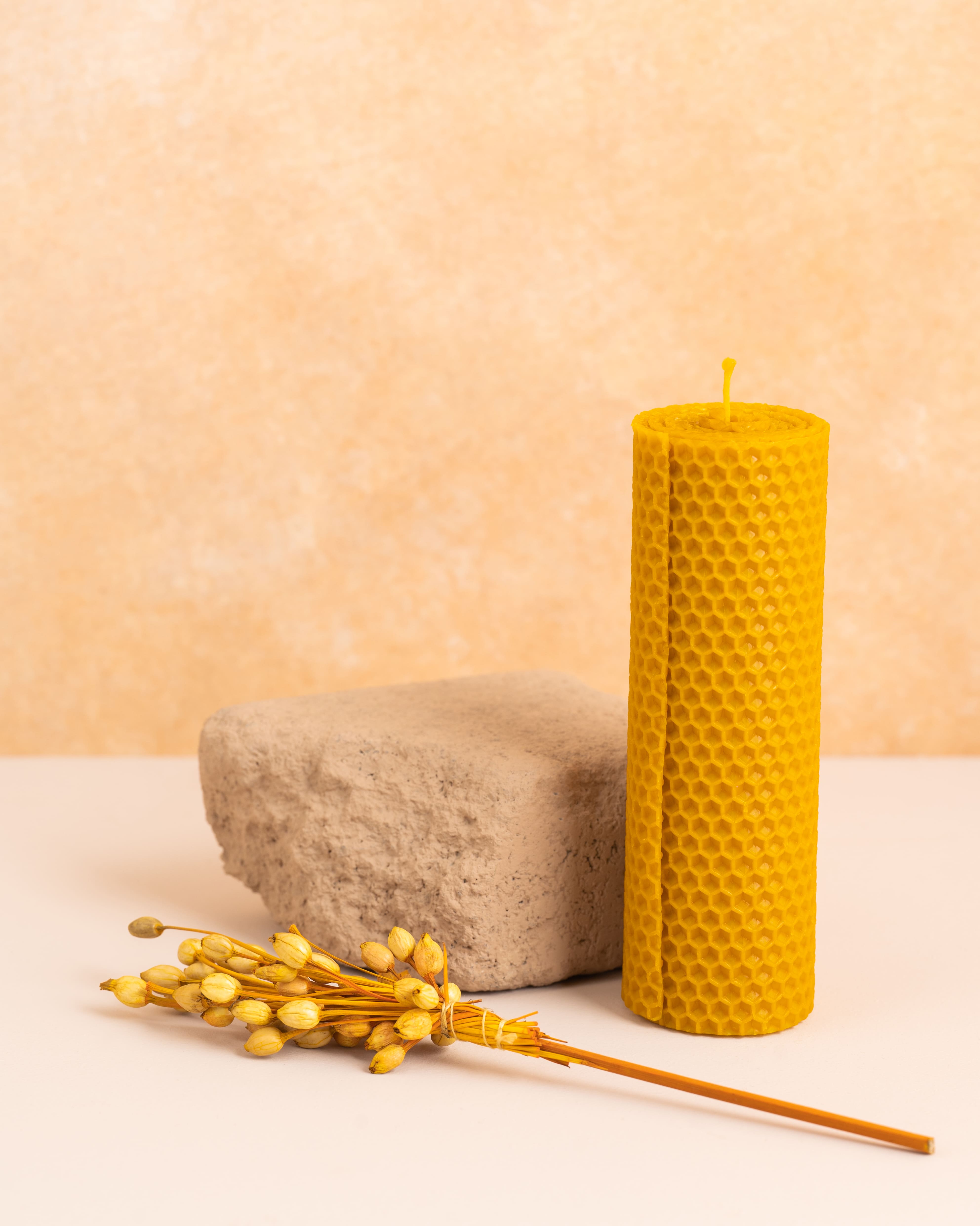 Vela alta em cera de abelha pura com 15 cm de altura, criada através de folhas de cera enroladas. Design artesanal com textura hexagonal dos favos de mel, proporcionando charme e autenticidade à decoração.