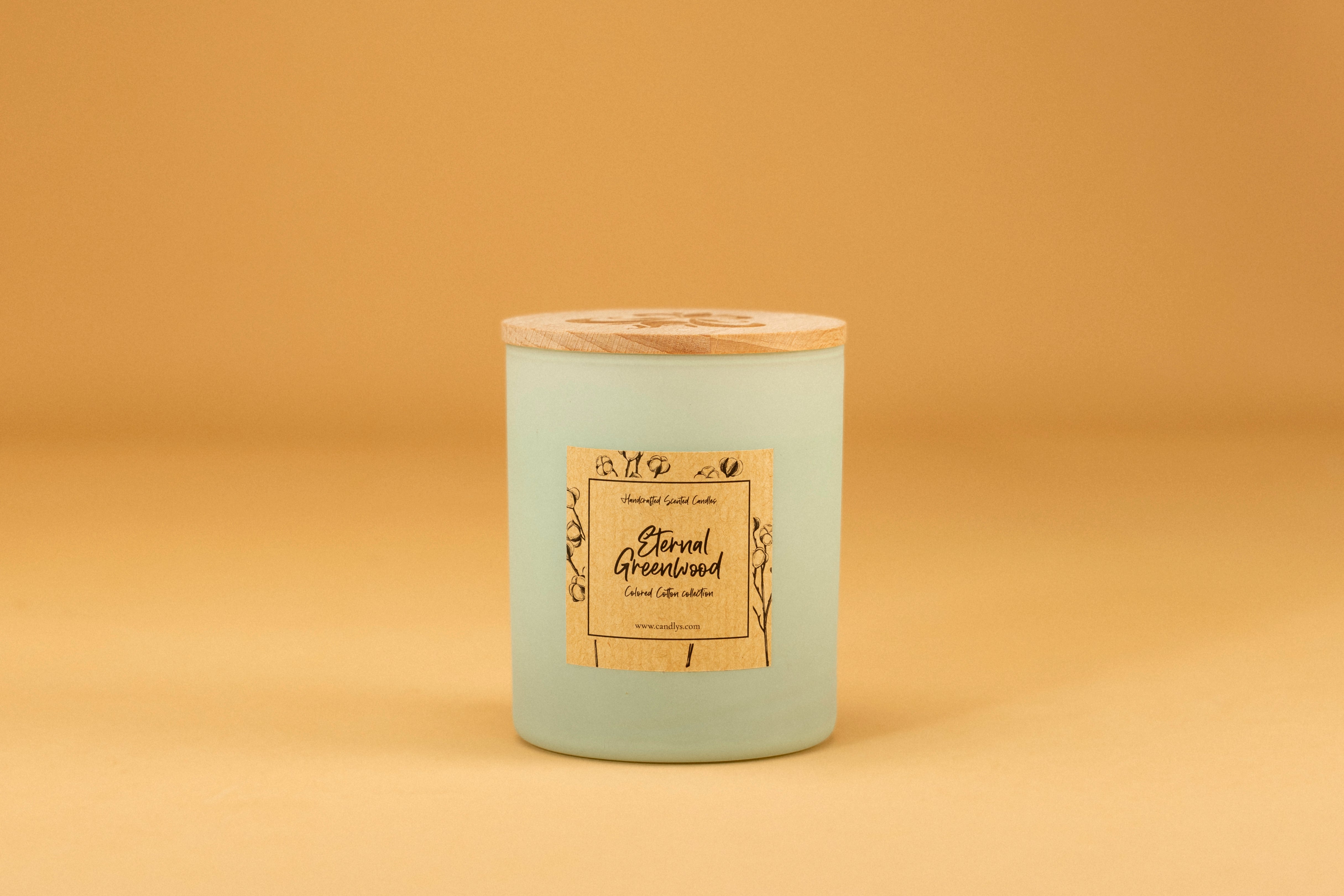 Vela Eternal Greenwood em copo verde mate com tampa de madeira e rótulo frontal, fundo bege minimalista.