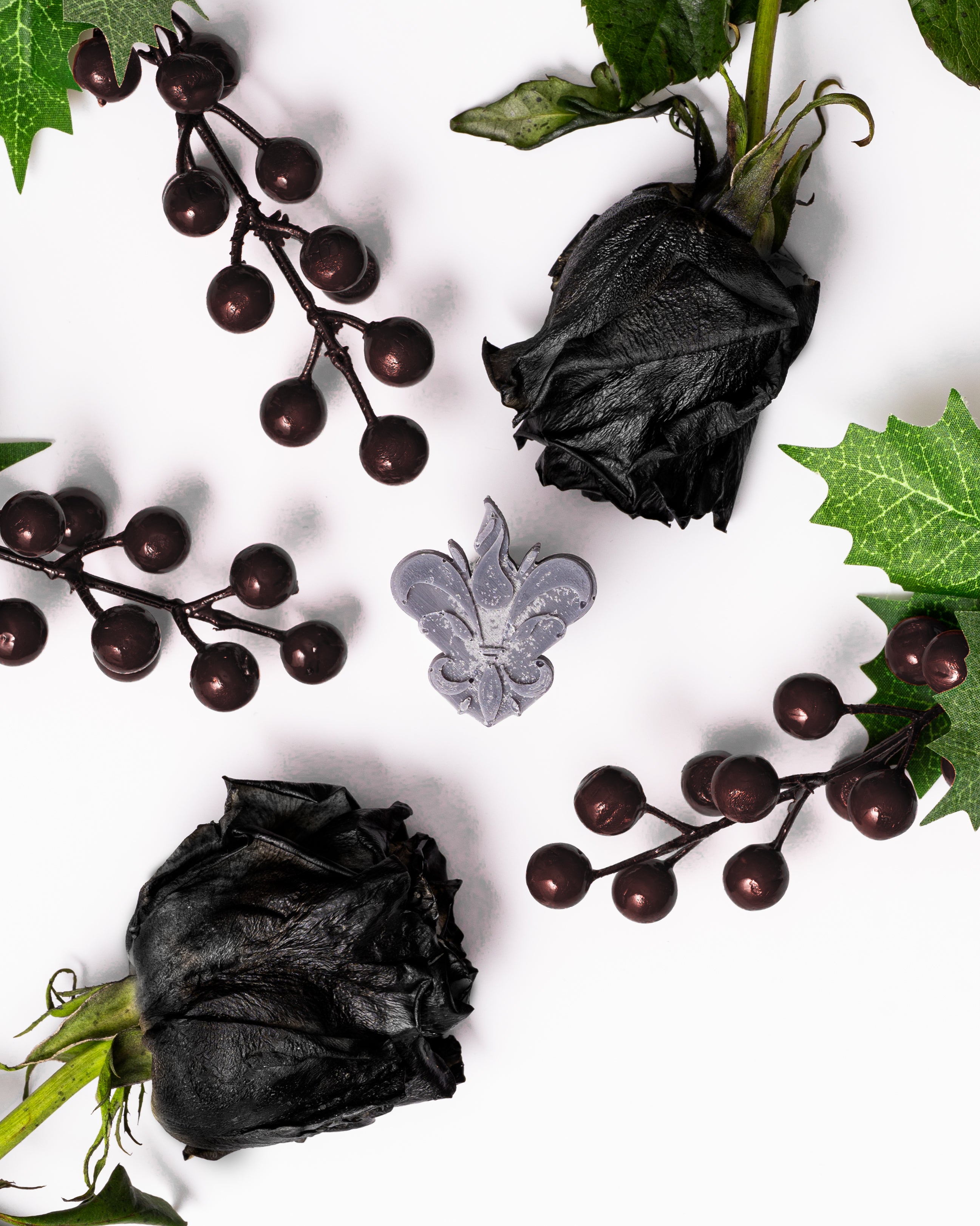 Wax melts Rosas Brancas & Groselha Preta representados por pétalas de rosas escuras secas e bagas de groselha preta sobre fundo branco, evocando uma fragrância floral intensa e frutada.
